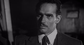 Movie still from “Touch of Evil” (1958), directed by Orson Welles – A black and white photo of a man in a suit and tie; Close Up shot, Low angle