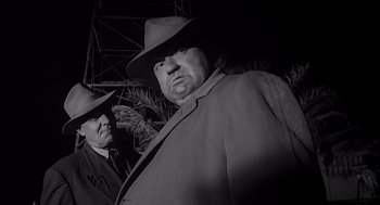 Movie still from “Touch of Evil” (1958), directed by Orson Welles – A man in a hat and a man in a suit and tie; Medium shot, Low angle