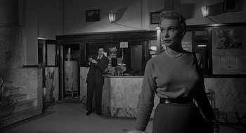 Movie still from “Touch of Evil” (1958), directed by Orson Welles – A man and a woman standing in front of a counter; Medium shot, Low angle