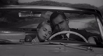 Movie still from “Touch of Evil” (1958), directed by Orson Welles – A man and a woman sitting in the driver's seat of a car; Close Up shot, High angle