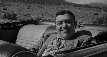 Movie still from “Touch of Evil” (1958), directed by Orson Welles – A black and white photo of a man sitting in the back seat of a car; Close Up shot, Over the shoulder angle