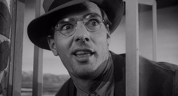 Movie still from “Touch of Evil” (1958), directed by Orson Welles – A black and white photo of a man wearing a hat and eyeglasses; Close Up shot, Low angle
