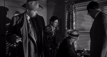 Movie still from “Touch of Evil” (1958), directed by Orson Welles – A group of men standing next to each other in front of a window; Medium shot, Low angle