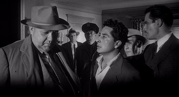 Movie still from “Touch of Evil” (1958), directed by Orson Welles – A black and white photo of a group of men in hats; Medium shot, Low angle