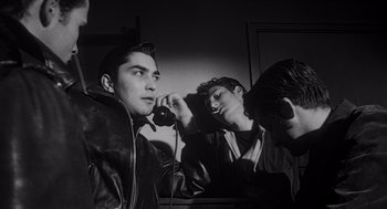 Movie still from “Touch of Evil” (1958), directed by Orson Welles – A group of young men sitting next to each other; Close Up shot, Low angle