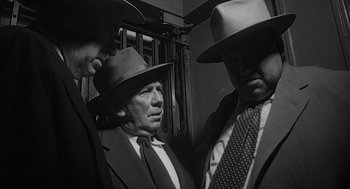 Movie still from “Touch of Evil” (1958), directed by Orson Welles – A group of men standing next to each other on top of a train; Medium shot, Low angle
