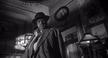 Movie still from “Touch of Evil” (1958), directed by Orson Welles – A man wearing a hat and a tie; Medium shot, Low angle