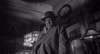 Movie still from “Touch of Evil” (1958), directed by Orson Welles – A man wearing a hat and a suit; Medium shot, Low angle