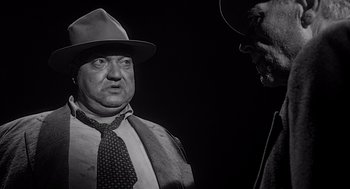 Movie still from “Touch of Evil” (1958), directed by Orson Welles – A black and white photo of a man wearing a hat and a tie; Close Up shot, Low angle