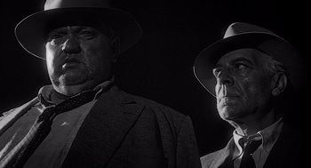 Movie still from “Touch of Evil” (1958), directed by Orson Welles – A black and white photo of two men in suits and hats; Close Up shot, Low angle