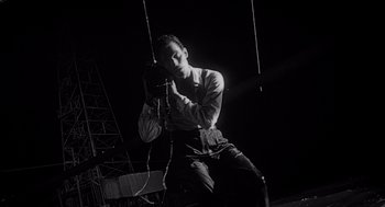 Movie still from “Touch of Evil” (1958), directed by Orson Welles – A black - and - white photo of a man holding a microphone; Medium shot, Low angle