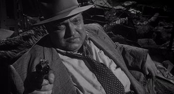 Movie still from “Touch of Evil” (1958), directed by Orson Welles – An old photo of a man holding a gun; Close Up shot, High angle