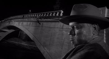 Movie still from “Touch of Evil” (1958), directed by Orson Welles – A black and white photo of a man wearing a hat; Close Up shot, Low angle