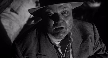Movie still from “Touch of Evil” (1958), directed by Orson Welles – An older man wearing a hat and a suit; Close Up shot, Low angle