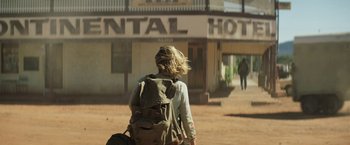 Movie still from “Tracks” (2013), directed by John Curran – A woman walking down a street with a backpack; Wide shot, Low angle