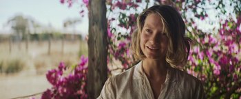 Movie still from “Tracks” (2013), directed by John Curran – A person smiling near a tree; Close Up shot, Over the shoulder angle