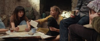 Movie still from “Tracks” (2013), directed by John Curran – A woman sitting at a table with a black dog; Medium shot, Over the shoulder angle