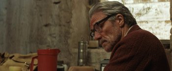 Movie still from “Tracks” (2013), directed by John Curran – An older man wearing glasses looking down at something; Close Up shot, Over the shoulder angle