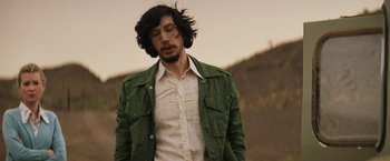 Movie still from “Tracks” (2013), directed by John Curran – A man with long hair and a green jacket is standing outside; Medium shot, Low angle