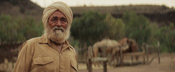 Movie still from “Tracks” (2013), directed by John Curran – An old man with a beard and a yellow turban; Close Up shot, Over the shoulder angle