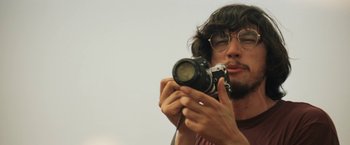 Movie still from “Tracks” (2013), directed by John Curran – A man holding a camera up to his face; Close Up shot, Low angle