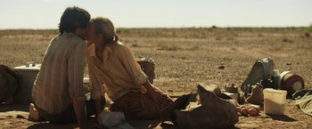 Movie still from “Tracks” (2013), directed by John Curran – A woman sitting on the ground in the desert; Medium shot, Over the shoulder angle