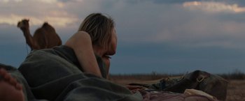 Movie still from “Tracks” (2013), directed by John Curran – A woman laying on a blanket in a field; Medium shot, Over the shoulder angle