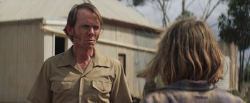 Movie still from “Tracks” (2013), directed by John Curran – A man wearing glasses and a brown shirt; Close Up shot, Over the shoulder angle