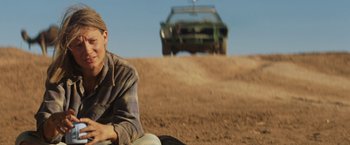 Movie still from “Tracks” (2013), directed by John Curran – A man sitting on the ground in front of a truck; Medium shot, Low angle
