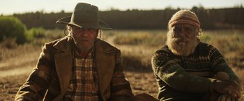 Movie still from “Tracks” (2013), directed by John Curran – A man and a woman sitting on a dirt field; Medium shot, Over the shoulder angle