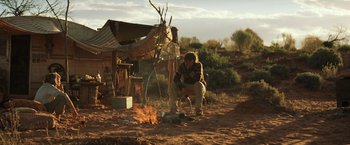 Movie still from “Tracks” (2013), directed by John Curran – A man sitting on a chair in front of an open fire; Wide shot, Low angle