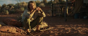 Movie still from “Tracks” (2013), directed by John Curran – A woman sitting on the ground in the dirt; Wide shot, Over the shoulder angle