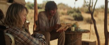 Movie still from “Tracks” (2013), directed by John Curran – A man sitting on top of a wooden bench reading a book; Medium shot, Over the shoulder angle