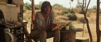 Movie still from “Tracks” (2013), directed by John Curran – A man sitting on top of a wooden bench; Medium shot, Over the shoulder angle