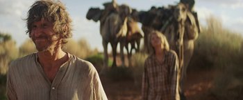 Movie still from “Tracks” (2013), directed by John Curran – Two people standing in front of a herd of elephants; Close Up shot, Over the shoulder angle
