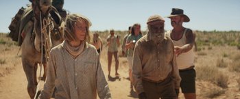 Movie still from “Tracks” (2013), directed by John Curran – A group of people walking down a dirt road; Medium shot, Over the shoulder angle