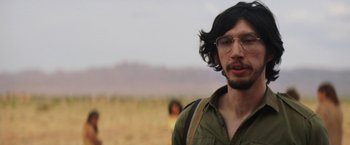 Movie still from “Tracks” (2013), directed by John Curran – A man with long hair and glasses is standing in a field; Close Up shot, Over the shoulder angle