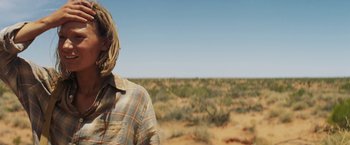 Movie still from “Tracks” (2013), directed by John Curran – A person standing in the middle of an open field; Close Up shot, Over the shoulder angle