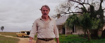 Movie still from “Tracks” (2013), directed by John Curran – An older man standing in front of a house; Medium shot, Low angle