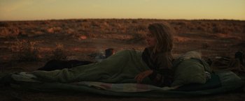 Movie still from “Tracks” (2013), directed by John Curran – A woman laying on a blanket in the desert; Wide shot, Over the shoulder angle