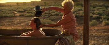 Movie still from “Tracks” (2013), directed by John Curran – An older woman is bathing a younger woman in a bath tub; Wide shot, Over the shoulder angle