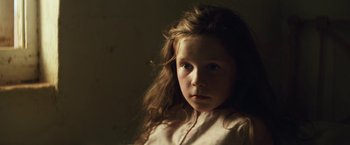 Movie still from “Tracks” (2013), directed by John Curran – A little girl with long brown hair is posing for a picture; Close Up shot, Low angle