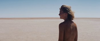Movie still from “Tracks” (2013), directed by John Curran – A woman standing in the middle of an empty beach; Medium shot, Over the shoulder angle
