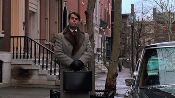 Movie still from “Trading Places” (1983), directed by John Landis – A man holding a briefcase while standing on the sidewalk; Wide shot, Low angle