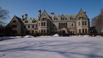 Movie still from “Trading Places” (1983), directed by John Landis – A very large stone mansion with a car parked in front of it; Extreme Wide shot, High angle