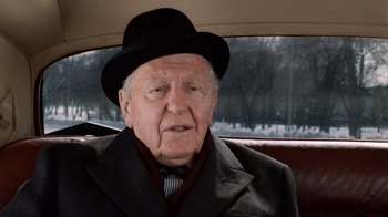 Movie still from “Trading Places” (1983), directed by John Landis – An old man wearing a black hat and a suit; Close Up shot, Over the shoulder angle