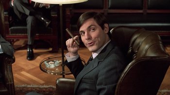 Movie still from “Trading Places” (1983), directed by John Landis – A man sitting in a chair holding a cigar; Medium shot, Low angle