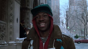 Movie still from “Trading Places” (1983), directed by John Landis – A man in a green hat and a brown jacket smiling; Close Up shot, Low angle