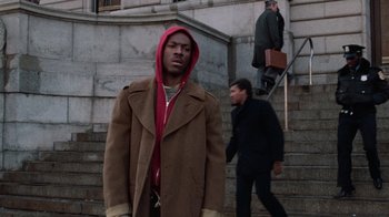 Movie still from “Trading Places” (1983), directed by John Landis – A man wearing a brown coat and a red hood; Medium shot, Low angle