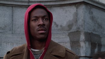 Movie still from “Trading Places” (1983), directed by John Landis – A young man wearing a brown jacket and a red hooded jacket; Close Up shot, Low angle